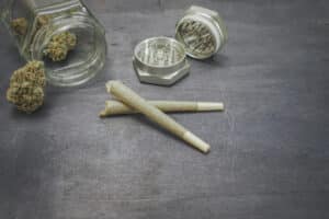 Pre-rolled CBD medical marijuana and hemp leaves on black wood background. Organic and natural hemp-based cosmetic and beauty products. Medical cannabis concept. Still life.