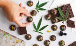 CBD chocolate bites with cool splattered cocoa butter designs on white background above view