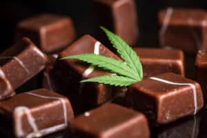 Cannabis sweets. Chocolate cubes with marijuana leaf on glass background. Closeup